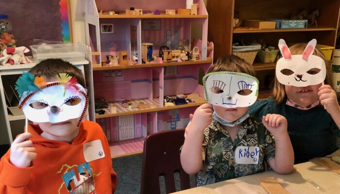 Three children wearing animal masks they made in the classroom
